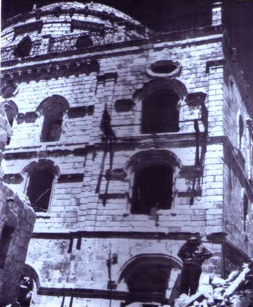11. Un soldat jordanien debout devant la 'Hourba atteinte de plusieurs obus lors de la guerre d'indépendance
