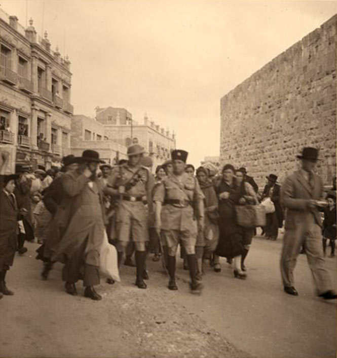 4. Un groupe de Juifs orthodoxes fuyant la Vieille ville de Jérusalem en 1936, protégés par des policiers juifs et des a...